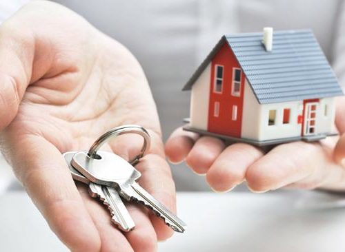 Hands holding miniature house and keys