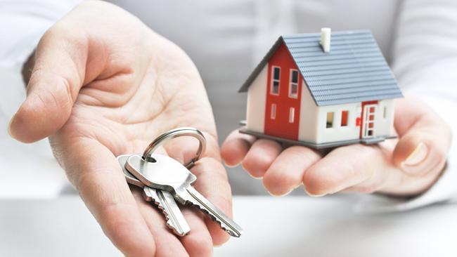 Hands holding miniature house and keys