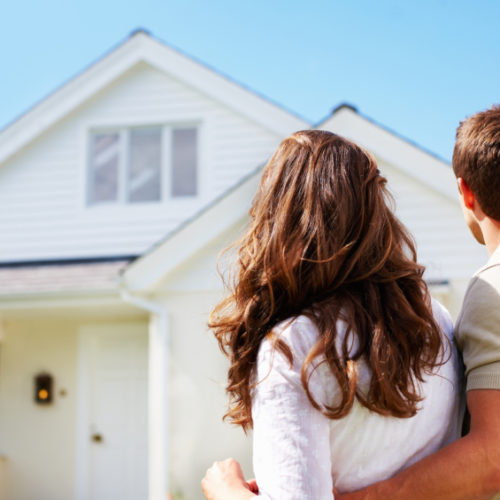 Couple standing in front of their first home