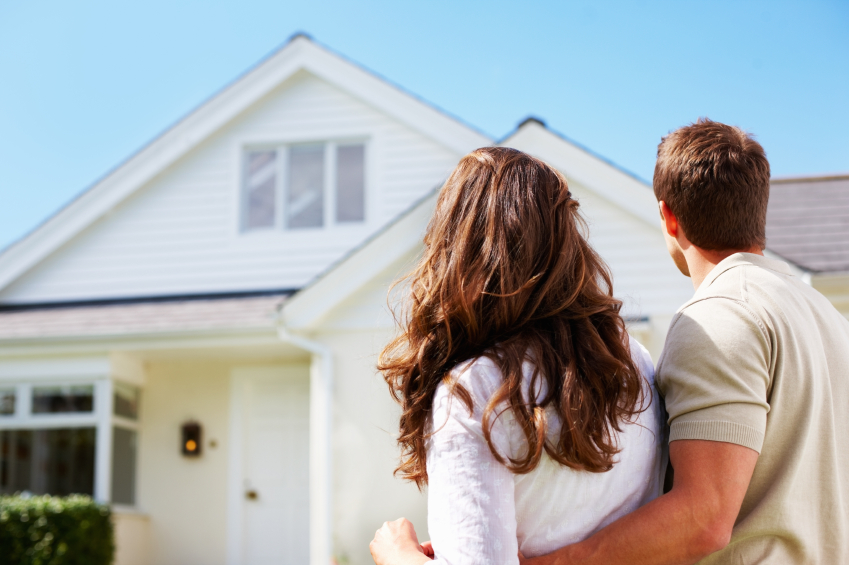 Couple standing in front of their first home