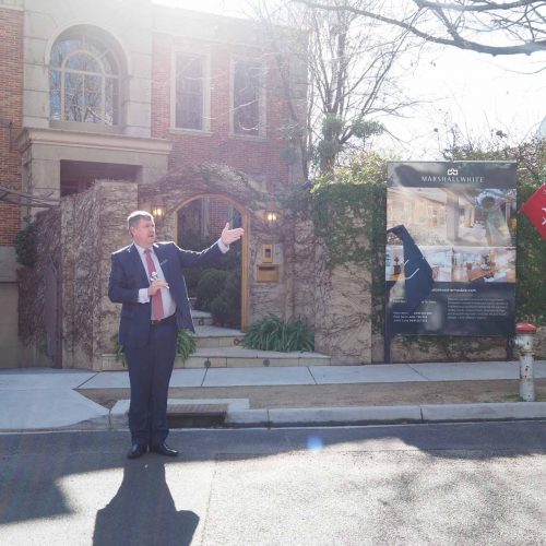 Auction snapshot - Auctioneer in front of large brick house