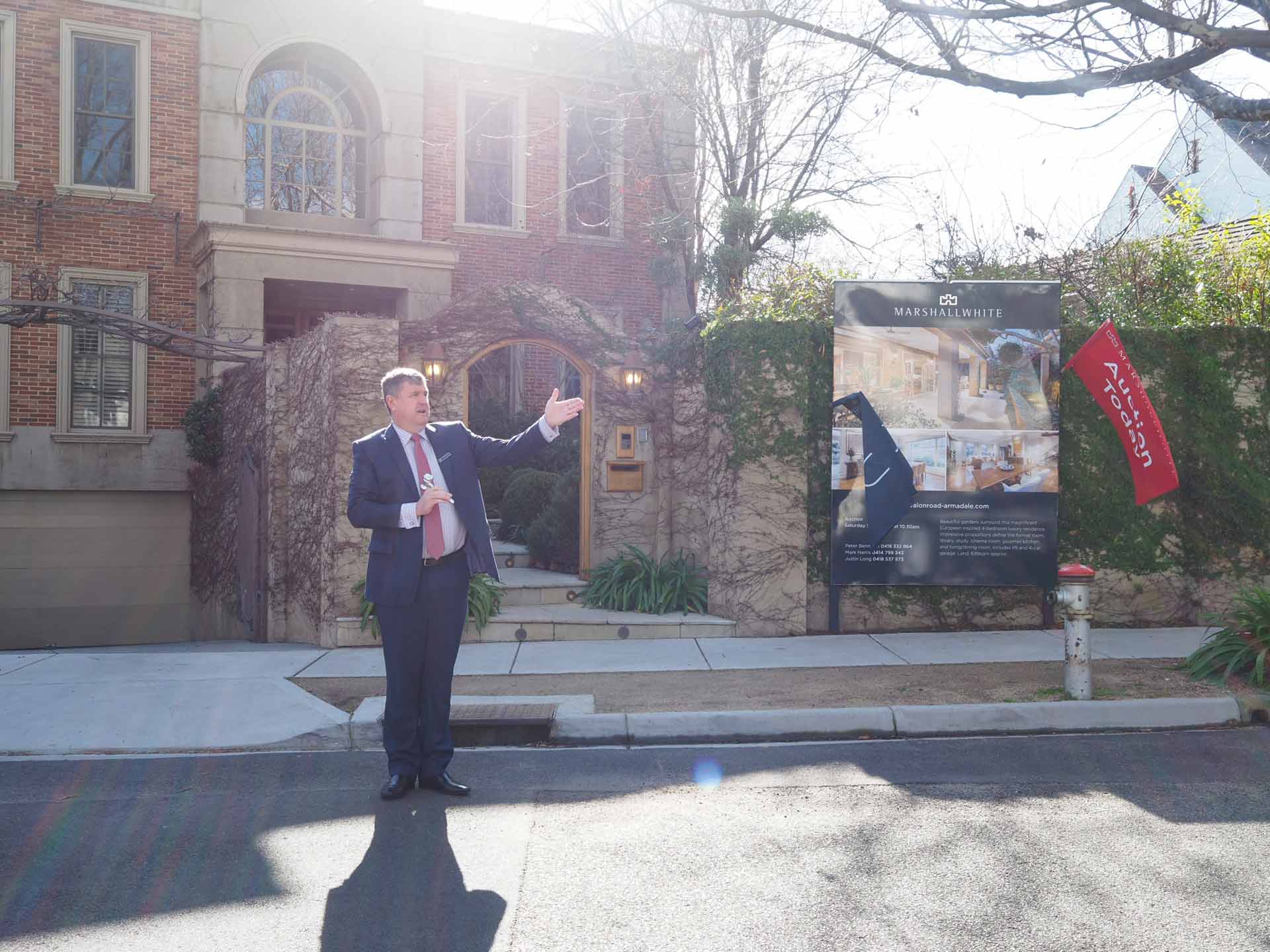 Auction snapshot - Auctioneer in front of large brick house