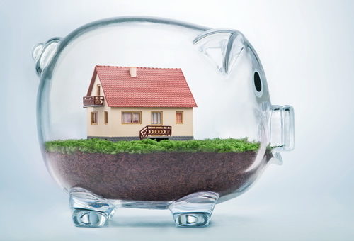 Miniature house in glass piggy bank