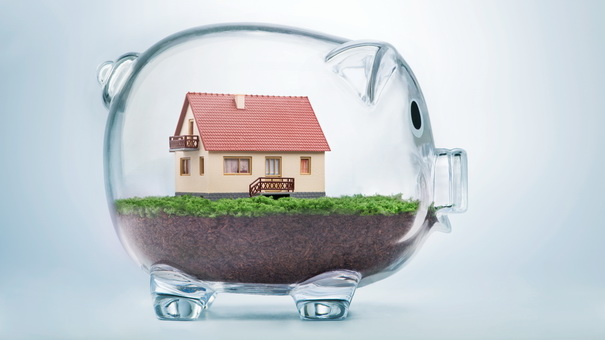 Miniature house in glass piggy bank