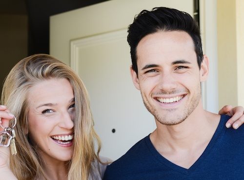 Happy couple holding keys to first home