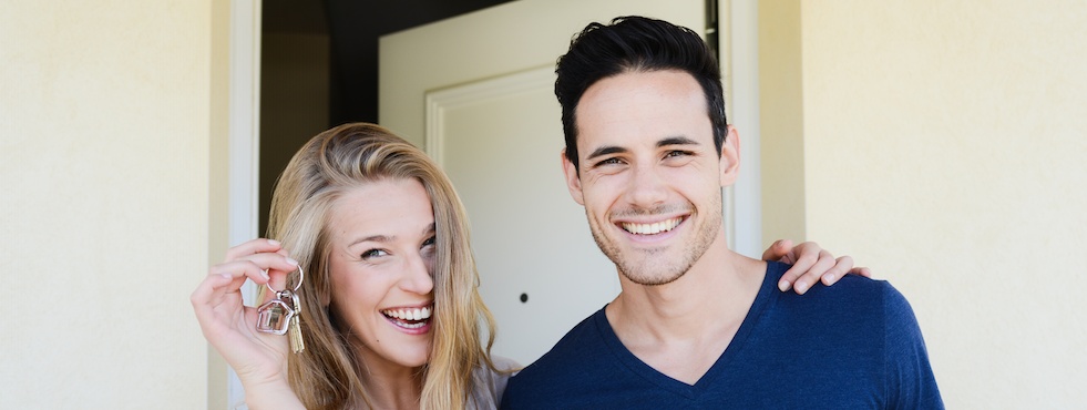 Happy couple holding keys to first home