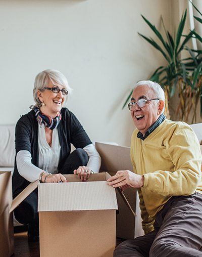 Happy elderly couple unpacking cardboard box